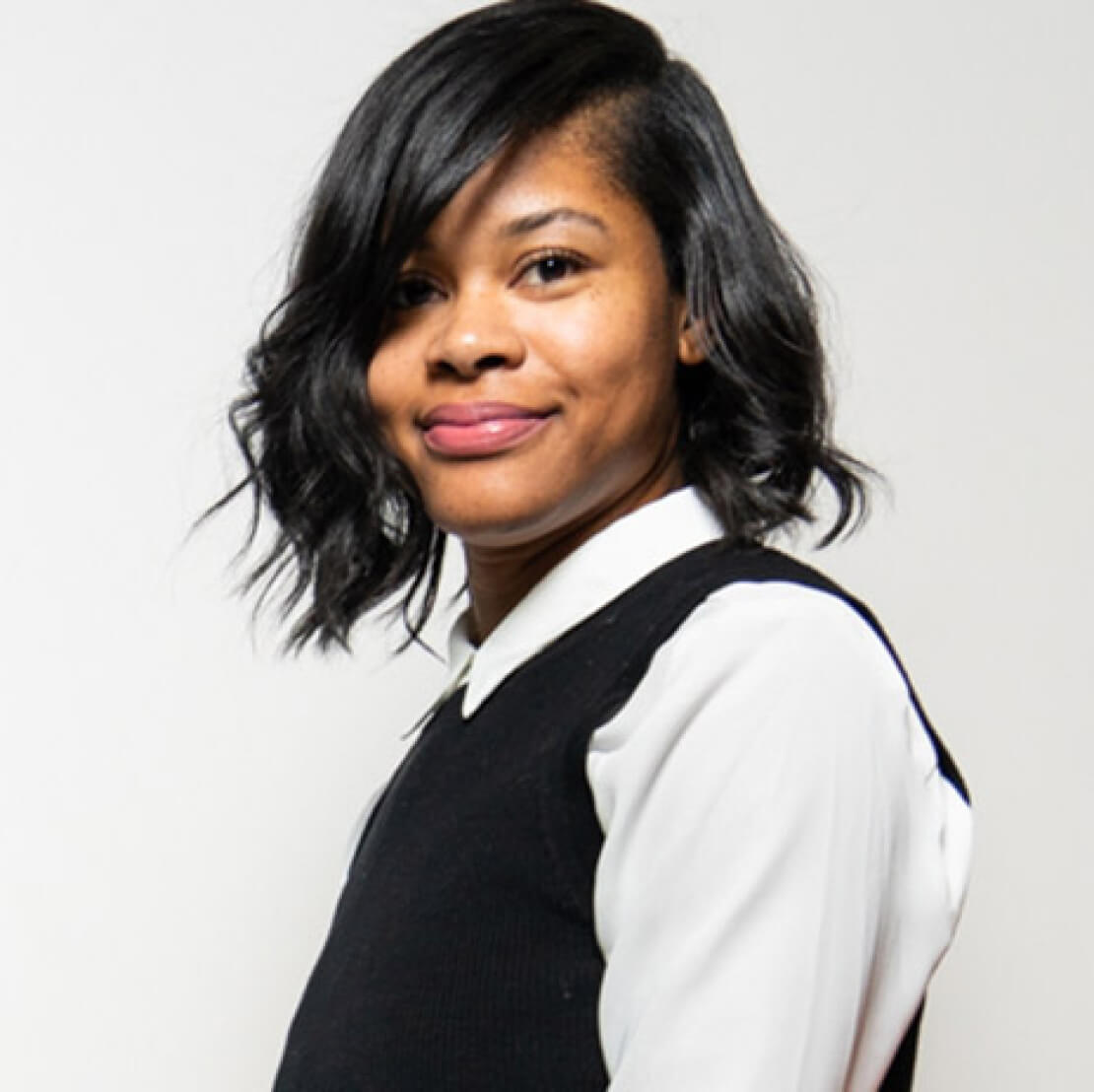 A woman with short hair and a black vest.