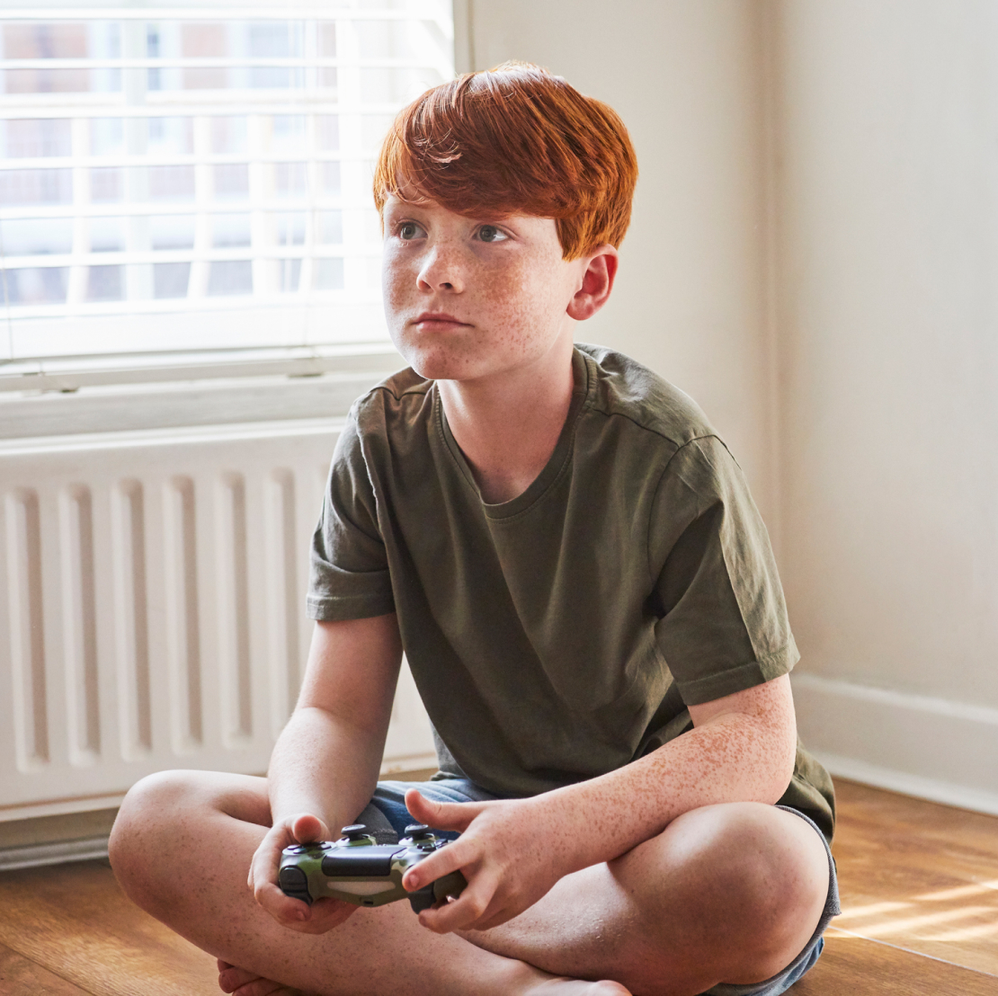 A young boy sitting on the floor, focused on playing a video game.