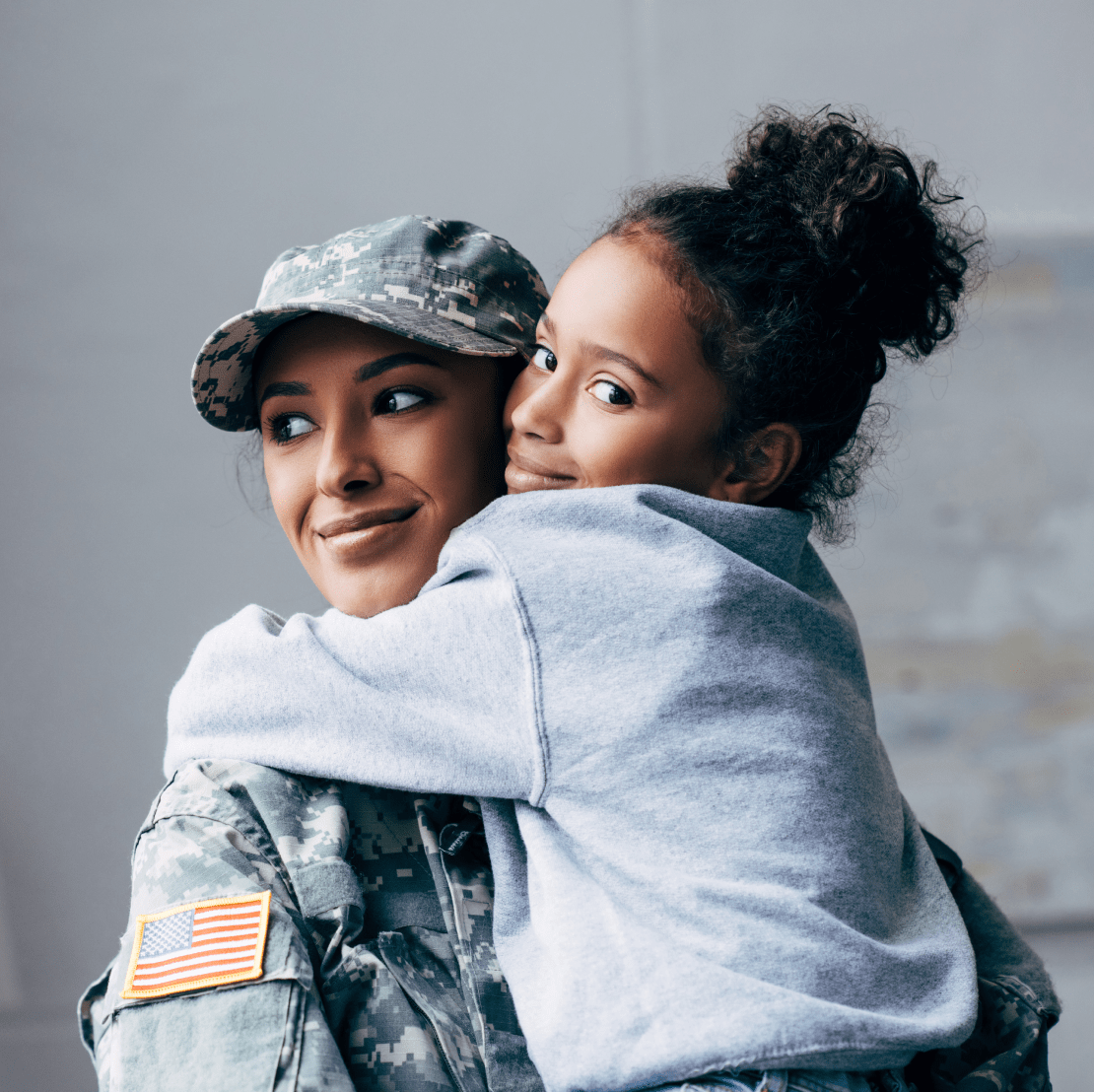 A female soldier embraces a young girl warmly, displaying a heartwarming bond between them.