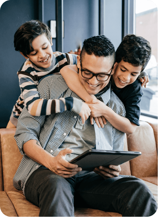 Father and two sons using a tablet, all facing the viewer